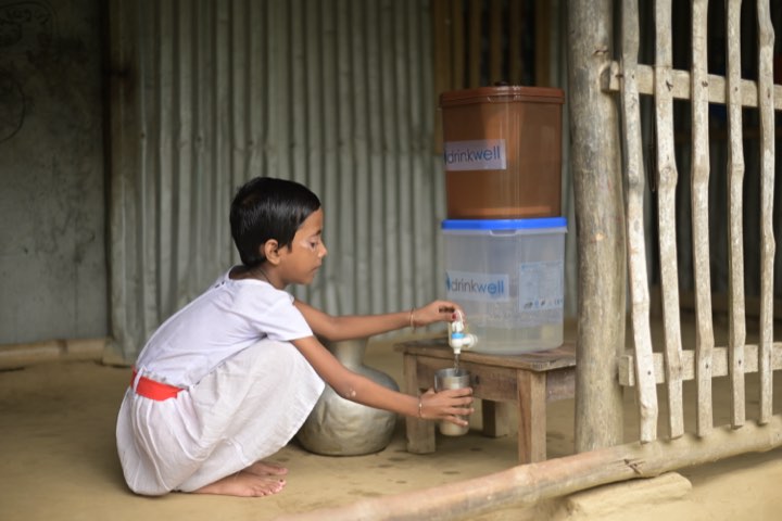 A girl fills a steel cup from a two-chamber Drinkwell tabletop filter at her home.